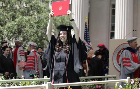 Happy female student exits the stage with her diploma