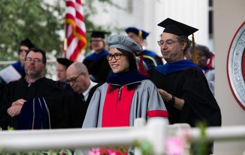 A female candidate is given her hood on stage; photo: Jake Belcher