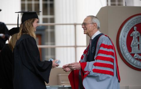 Image of President Reif handing a Congratulations scroll to a graduate