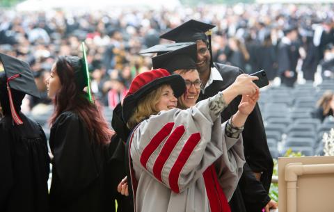 Image of a faculty member taking a photo with students on the stage at the Special Ceremony for the Classes of 2020 and 2021