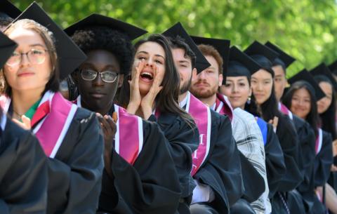 Image of graduates cheering on their classmates as they perform during the Undergraduate Ceremony