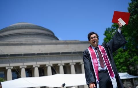 Image of a graduate after the Undergraduate Ceremony smiling and holding up his diploma