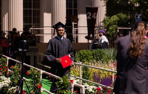 Image of a graduate walking off the Commencement stage with their diploma in hand