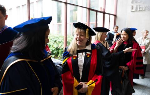 Image of faculty members in their regalia talking before the OneMIT Commencement Ceremony